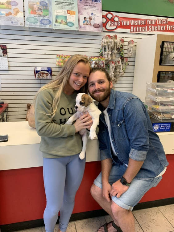 Two people holding a puppy.