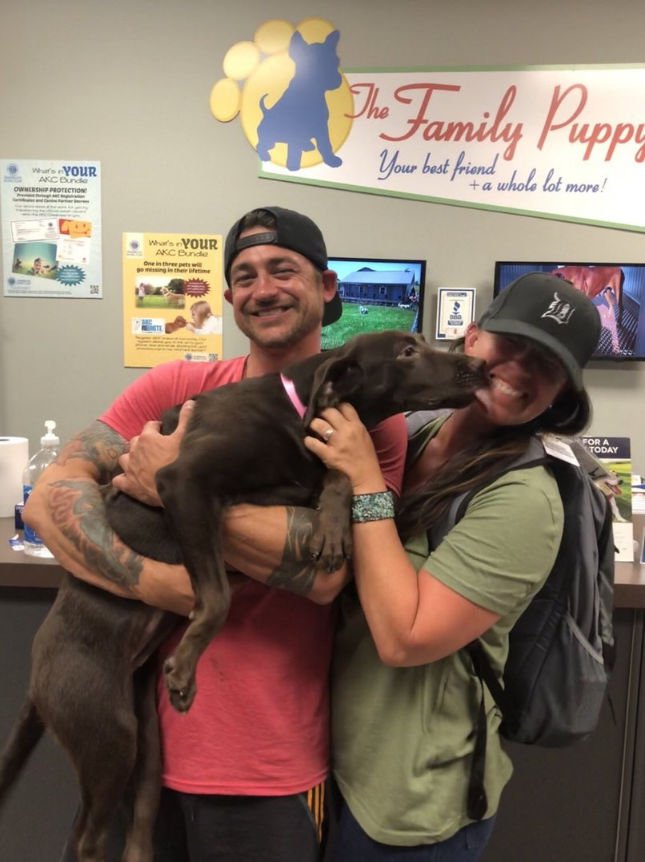 Two people holding a dog.