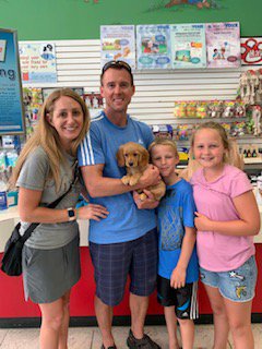 Two adults and two children holding a puppy.