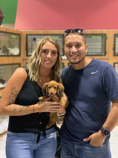 Two adults holding a puppy.