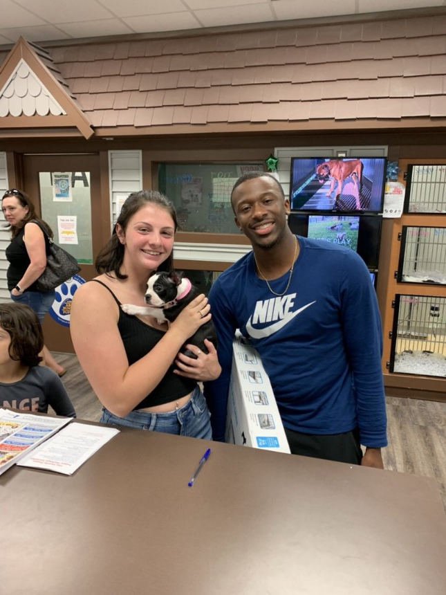 Two smiling people holding a puppy.