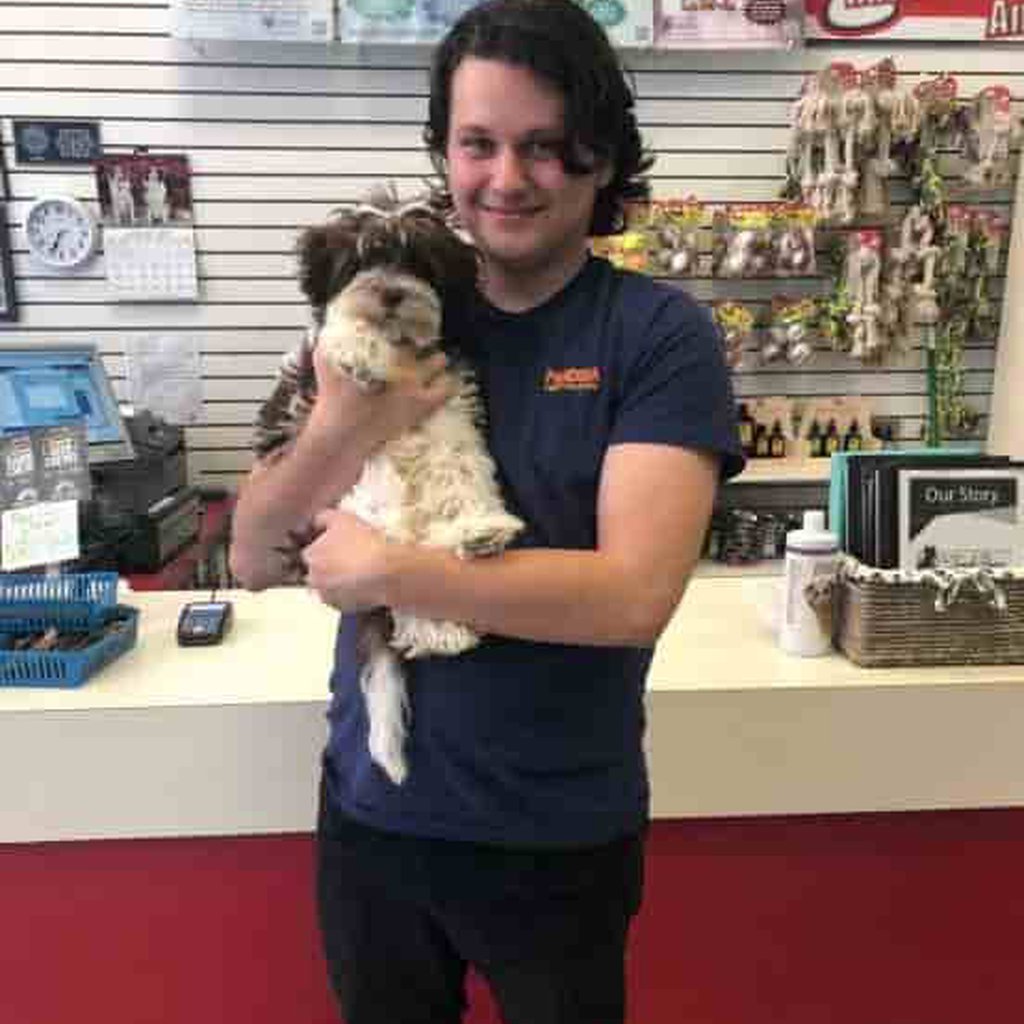 A person holding up a puppy and smiling.