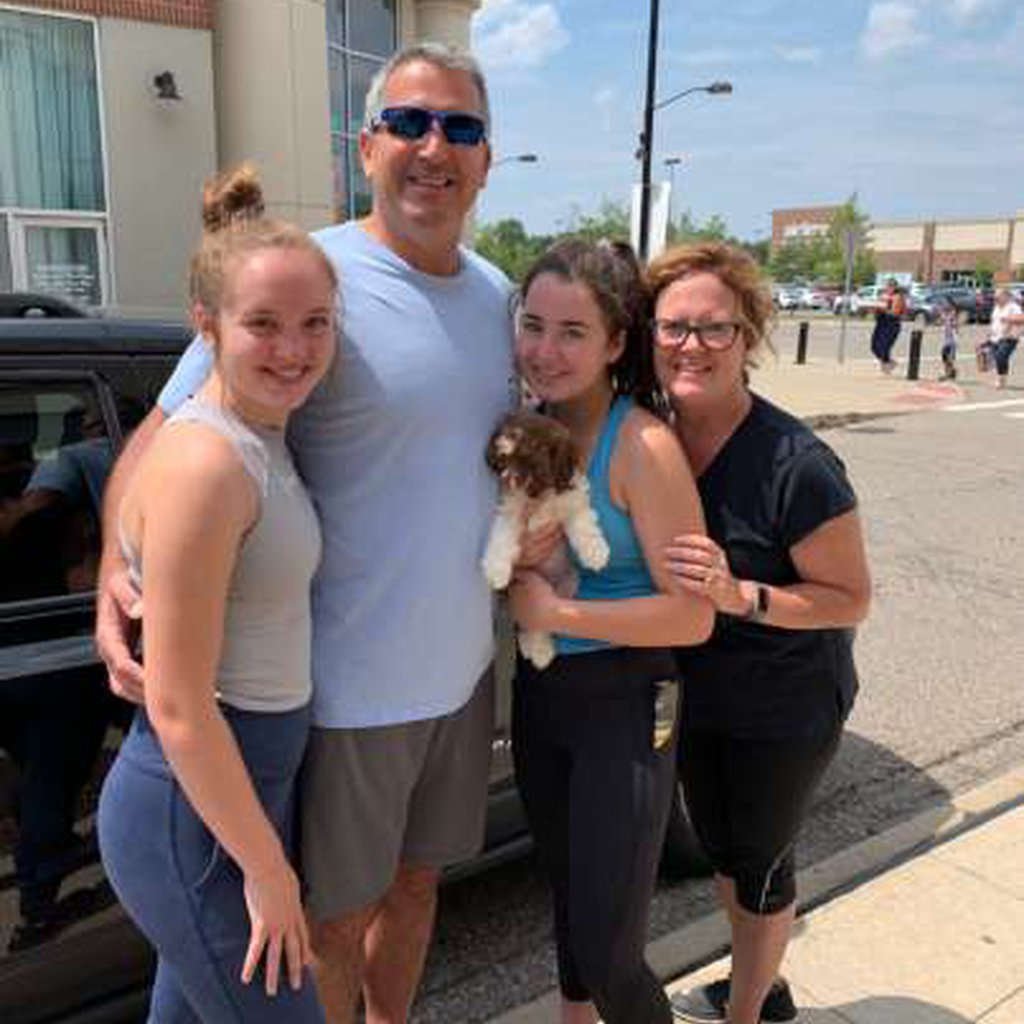 Four people holding a puppy.